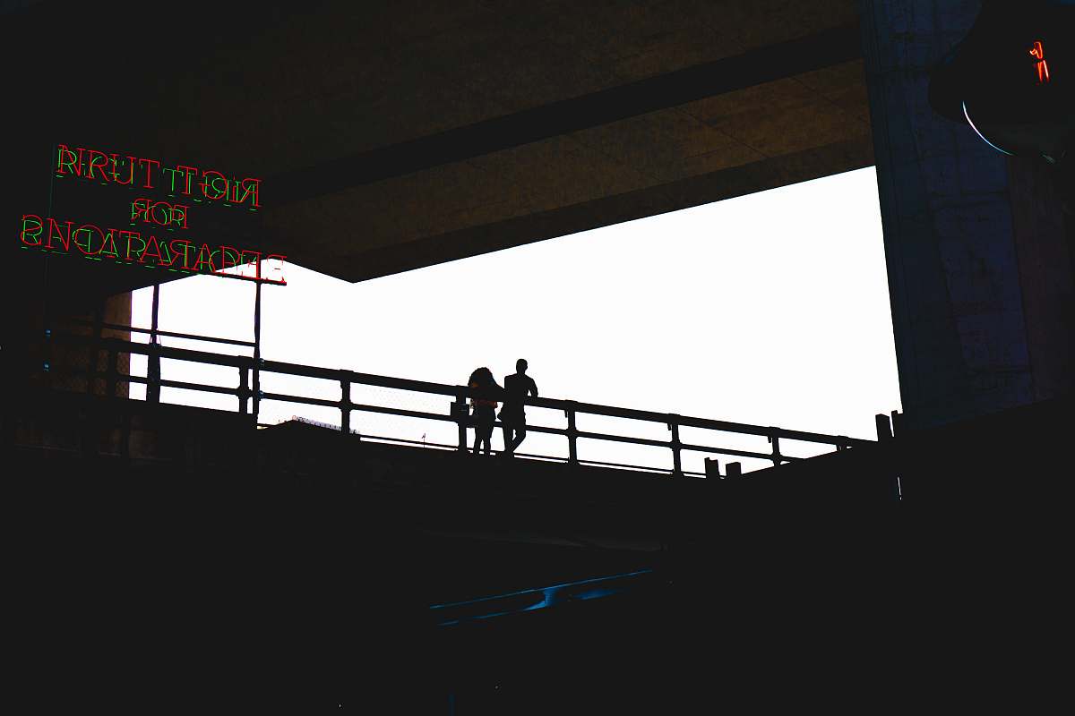new york silhouette photo of two person standing beside metal railings near LED signage united states